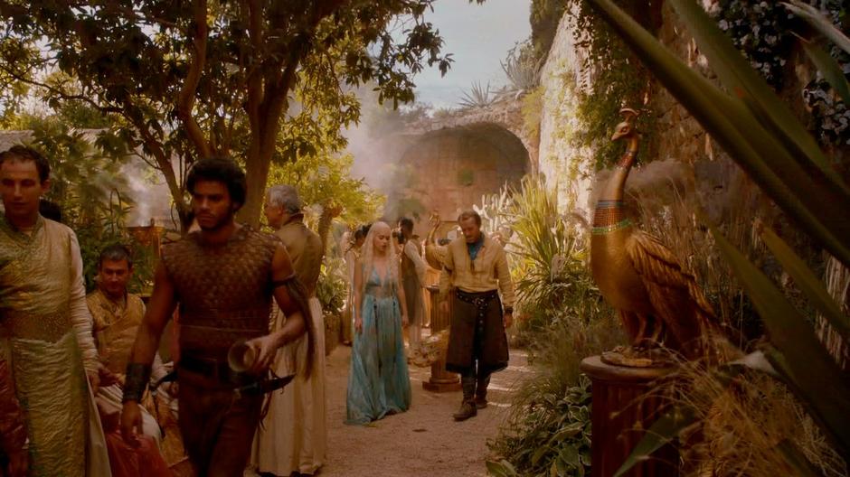 Daenerys and Bronn chat while walking through the party.