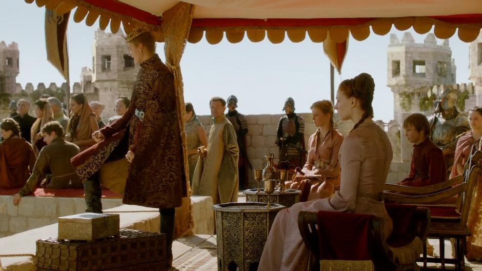Joffrey looks down at the dead fighter while Sansa sits behind disgusted.