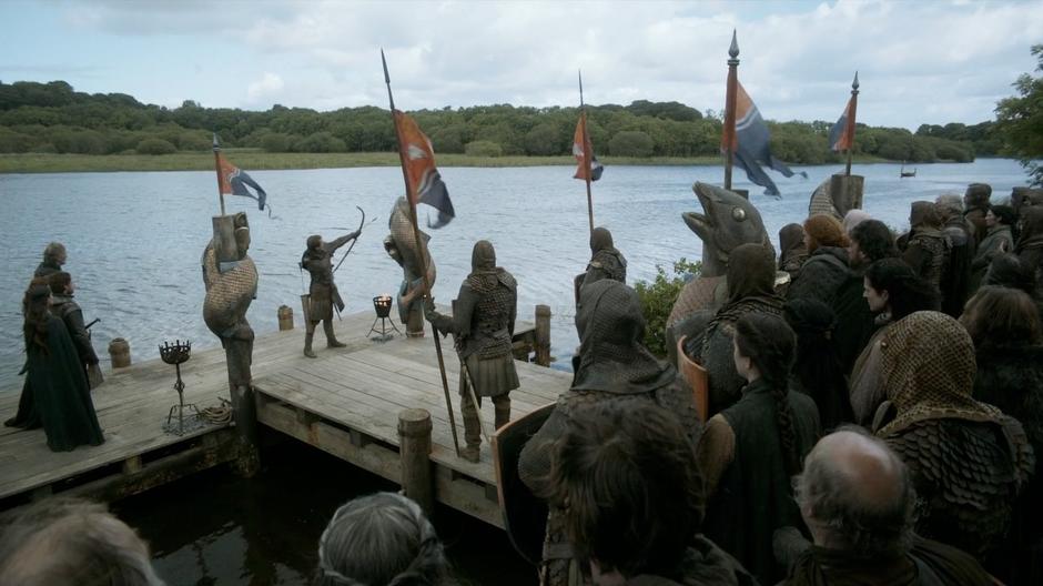 Edmure fires another arrow at the funeral boat floating farther downstream.