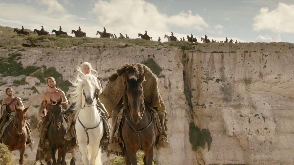 Daenerys and Khal Drogo lead the Dothraki riders along the edge of the cliff.