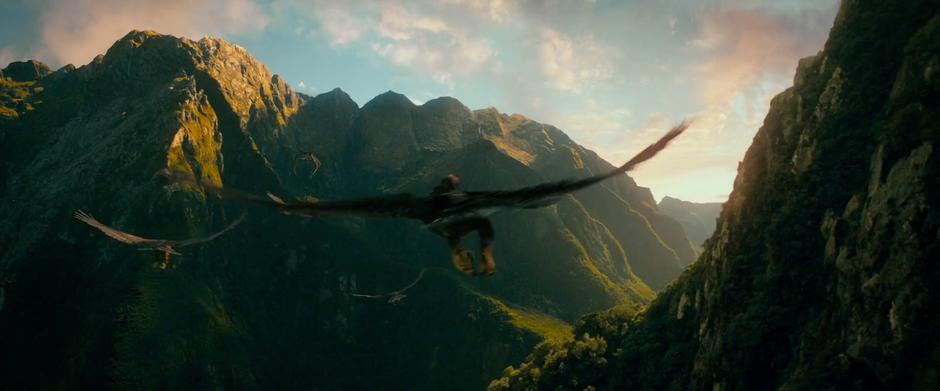 Eagles carrying Thorin's company fly through a mountain valley.
