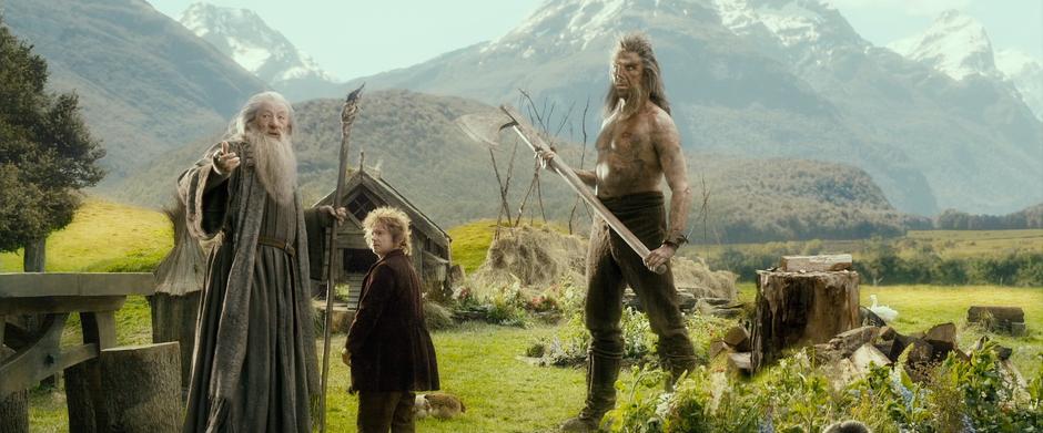 Gandalf motions to the dwarves while Beorn guardedly holds his ax.