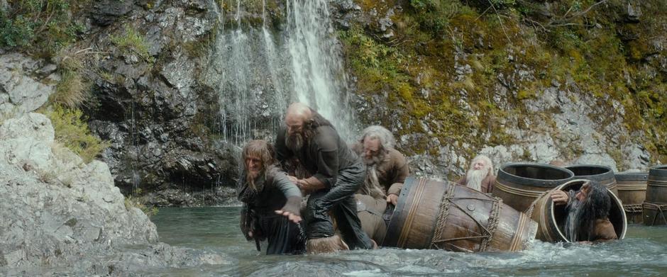 Dwalin helps Ori out of the river while the other dwarves struggle in the back.