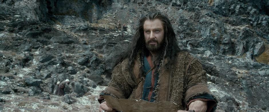 Thorin looks at the map while searching for the secret entrance.
