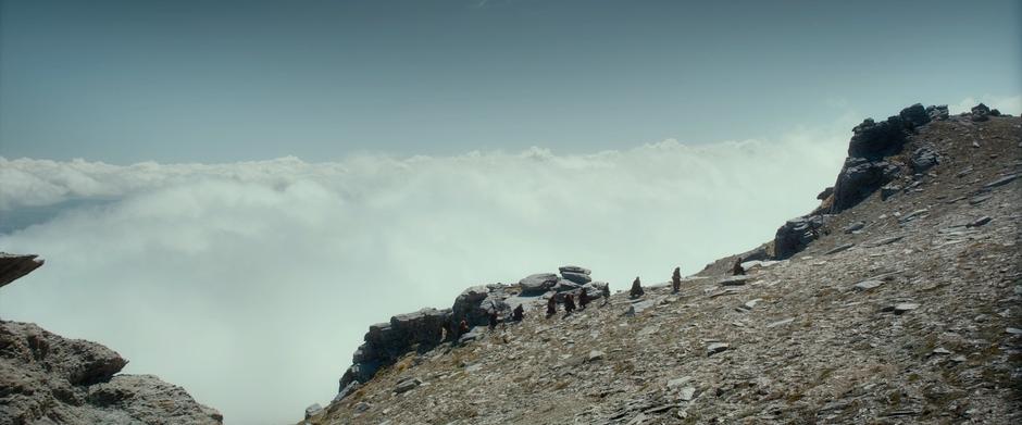 The company walks along a ridge line above some low-lying clouds.