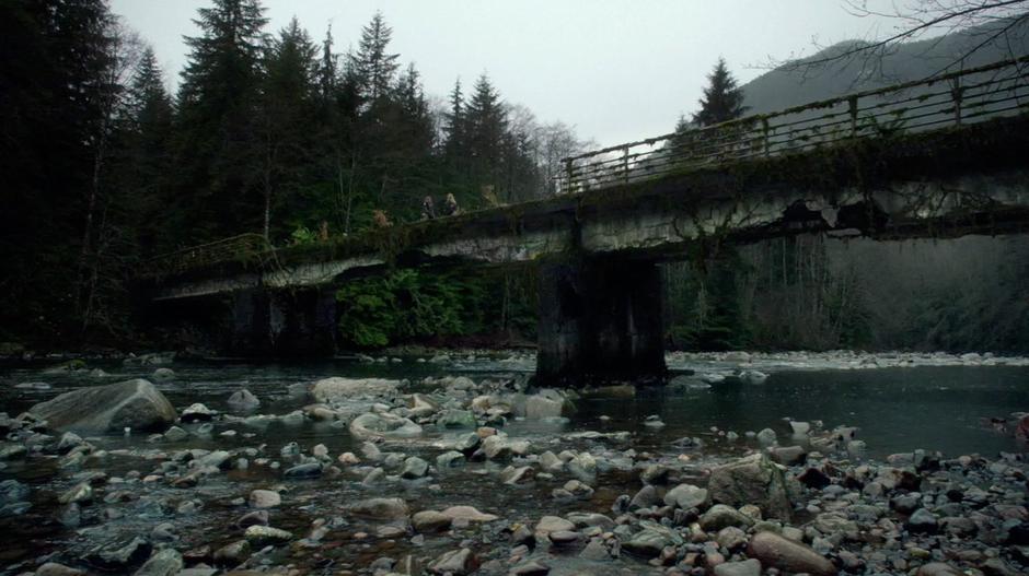 Clarke and Anya meet at the middle of a dilapidated bridge.