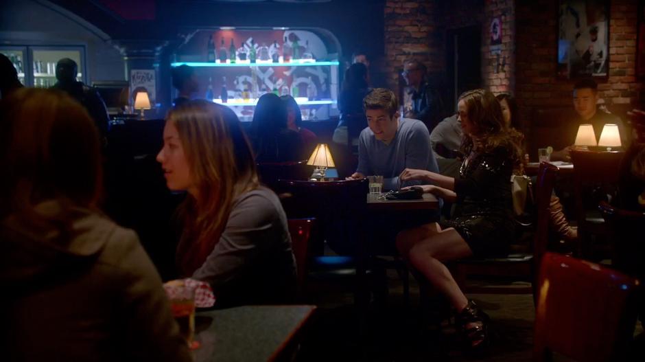 Caitlin and Barry share a drink at their table in the bar.