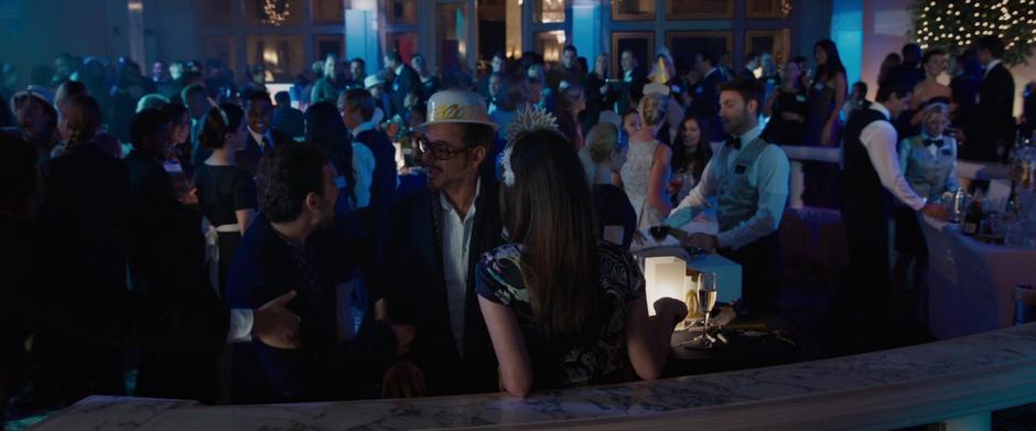 Tony Stark talks to some folks at the party while Maya Hansen stands by.