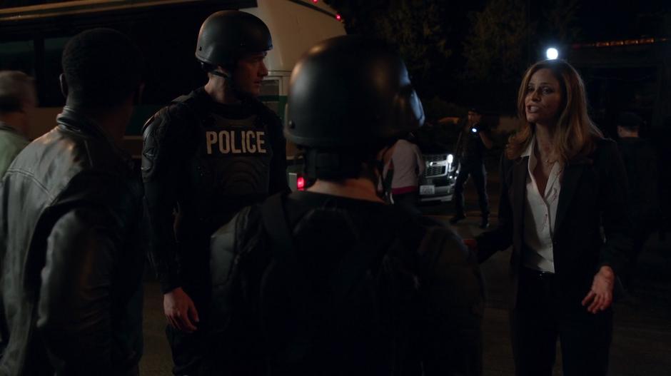 Vivian Stoll talks to Major, Liv, and Clive in front of the vehicles parked outside the garage.