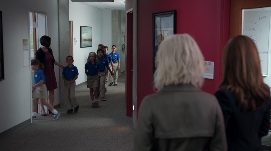 Liv and Vivian watch a group of zombie children being led into their classroom by a teacher.