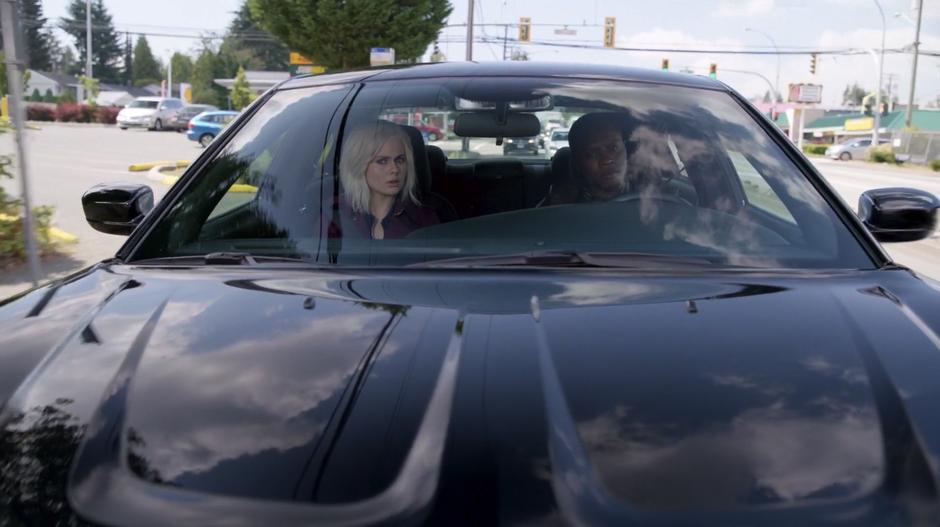 Liv and Clive drive down the street while listening to the radio.