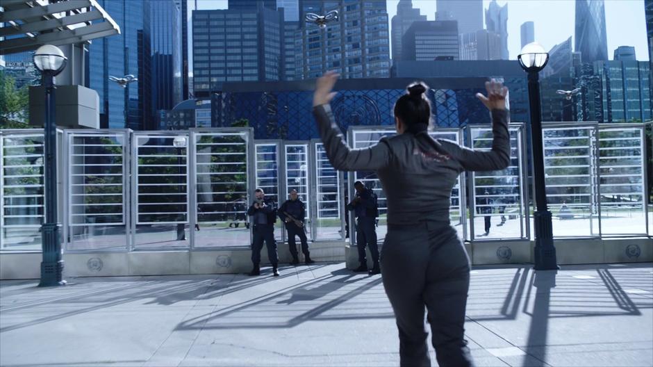 Bobbie runs up to three U.N. security guards at the checkpoint with her hands up.