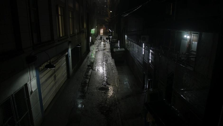 Julia & Quentin walk down a dark alley shining flashlights in front of them.