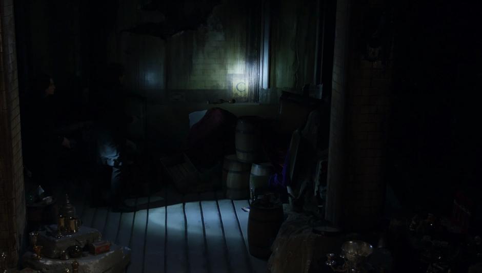 Julia shines her flashlight around the inside of the dark lair.