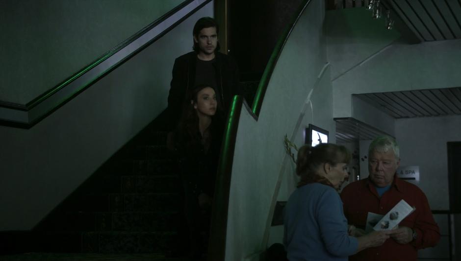 Julia & Quentin crouch on the stairs while Richard makes a distraction in the lobby.