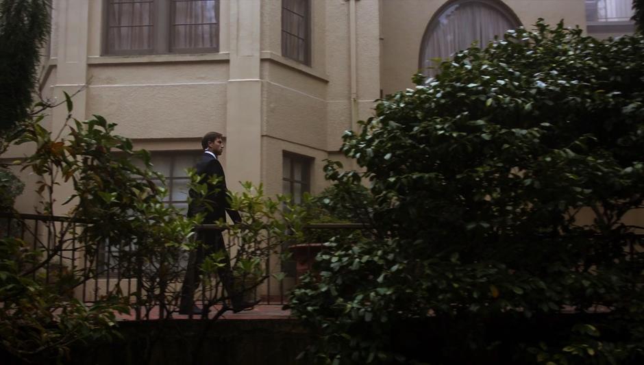 A guard walks along the porch in front of the mansion.