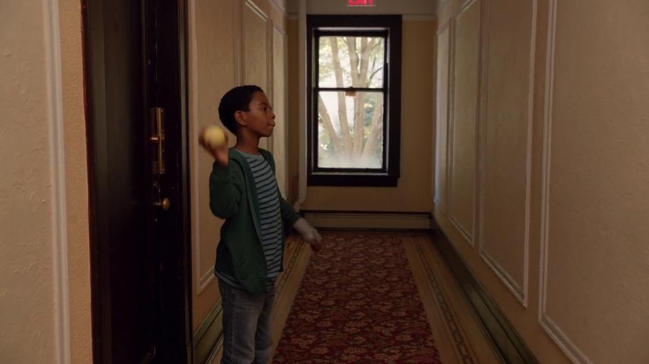Wally throws a ball against the wall in the hallway outside Clive's apartment.