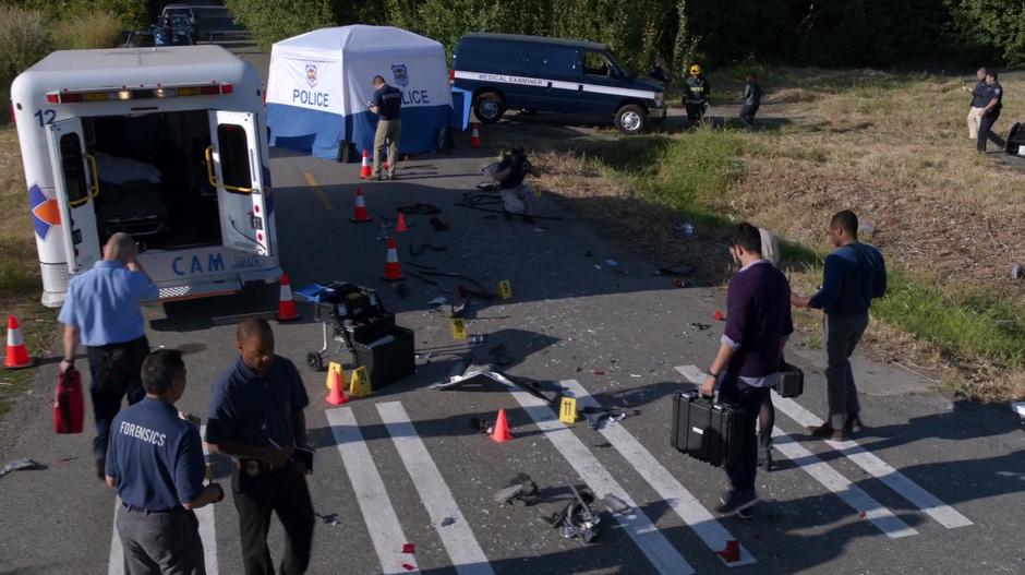 Clive approaches the crime scene with Liv and Ravi while other members of the emergency services mill around.