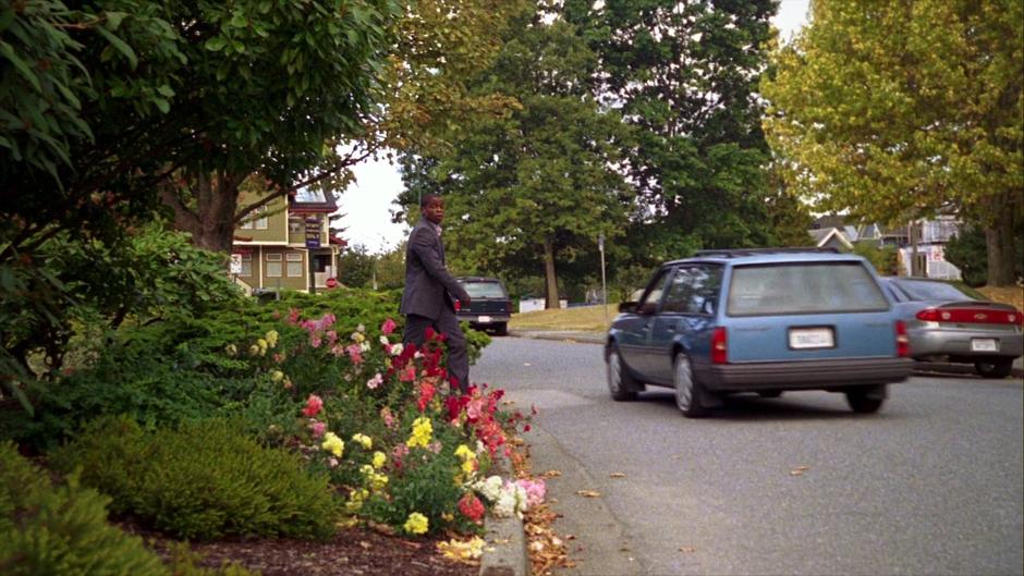 Gus comes out of the bushes and sneaks across the road towards the front of the Space Center.