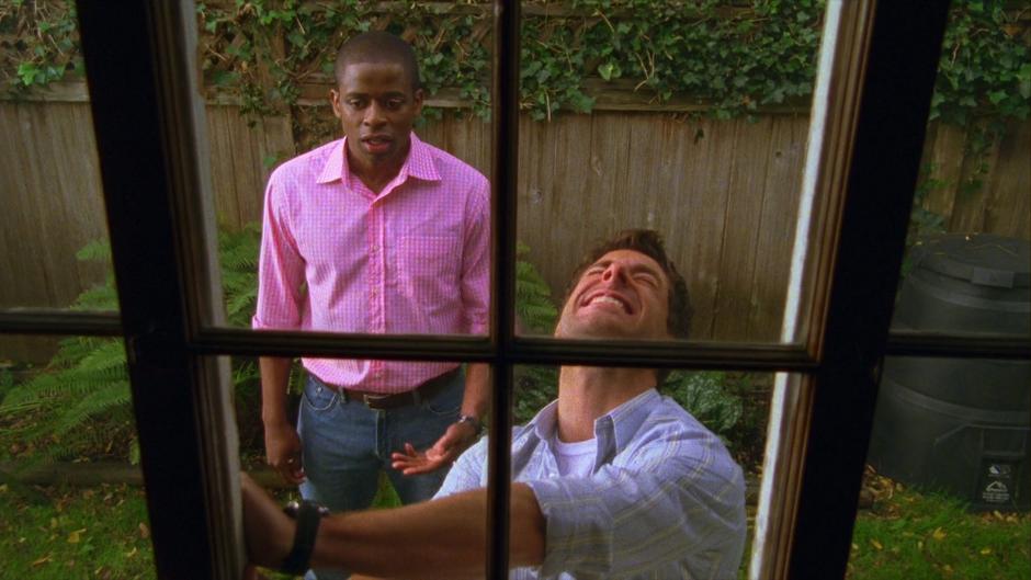 Gus looks on as Shawn struggles to open the window of Hugo's house.