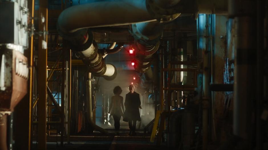 Bill and the Doctor walk down a grungy ship corridor near the entrance.