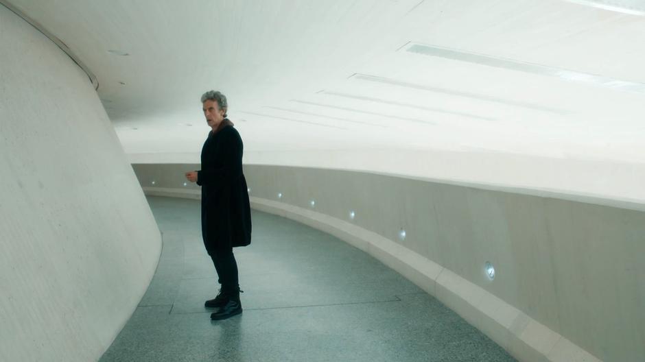 The Doctor looks down a curved corridor where an emoji-bot is waiting.