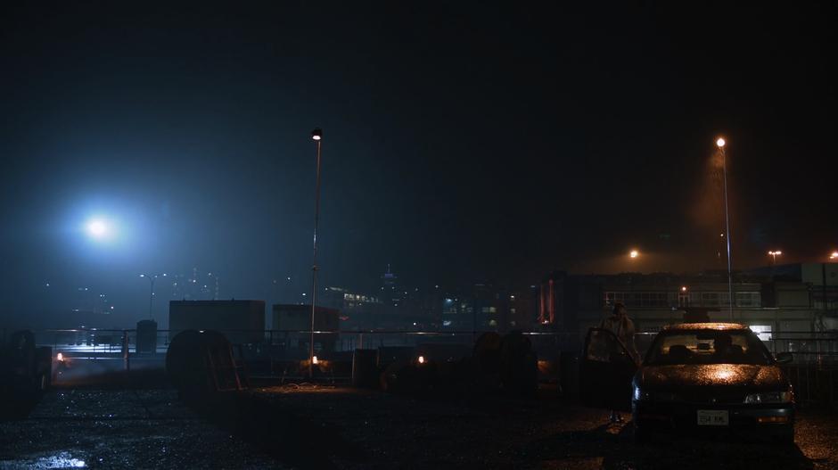 Kara enters the whistleblower's car with the skyline visible behind them.