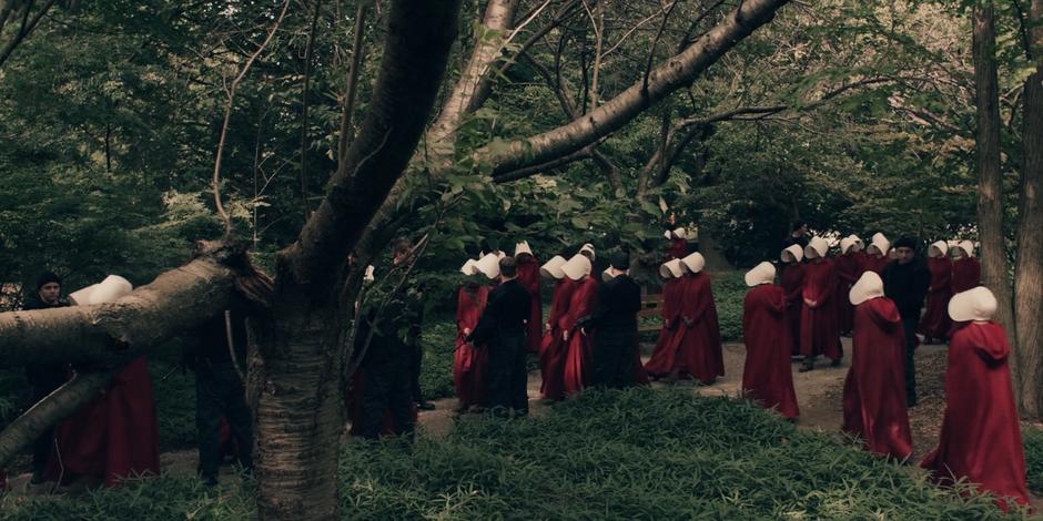 The handmaids walk through the paths converging on the stage area.