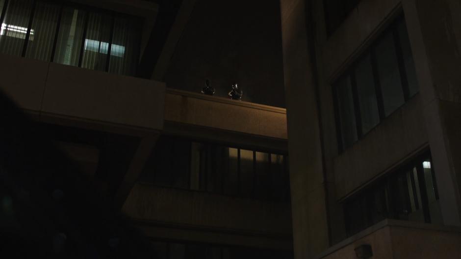 Oliver and Diggle look down from a rooftop high above.