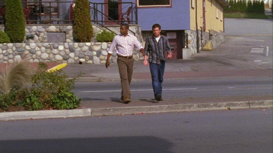 Gus and Shawn walk across the street towards the tanning salon and Shawn explains why he believes this is the correct place to investigate.