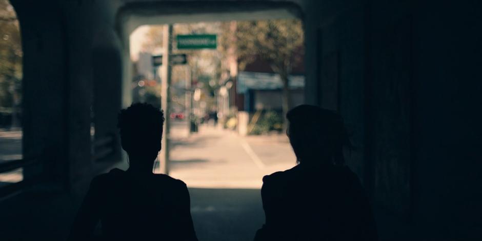 Moira and June jog out from the shadowed underpass.