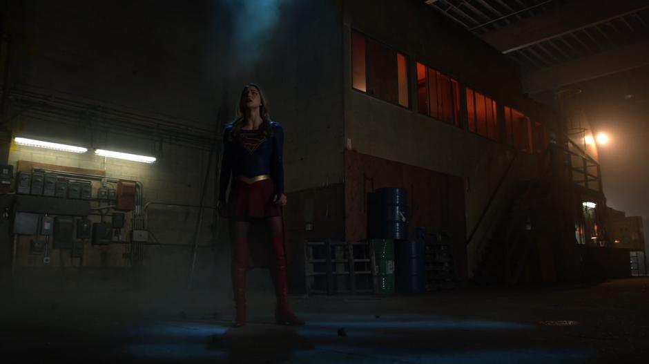 Kara lands in the warehouse after bursting through the ceiling and looks around.
