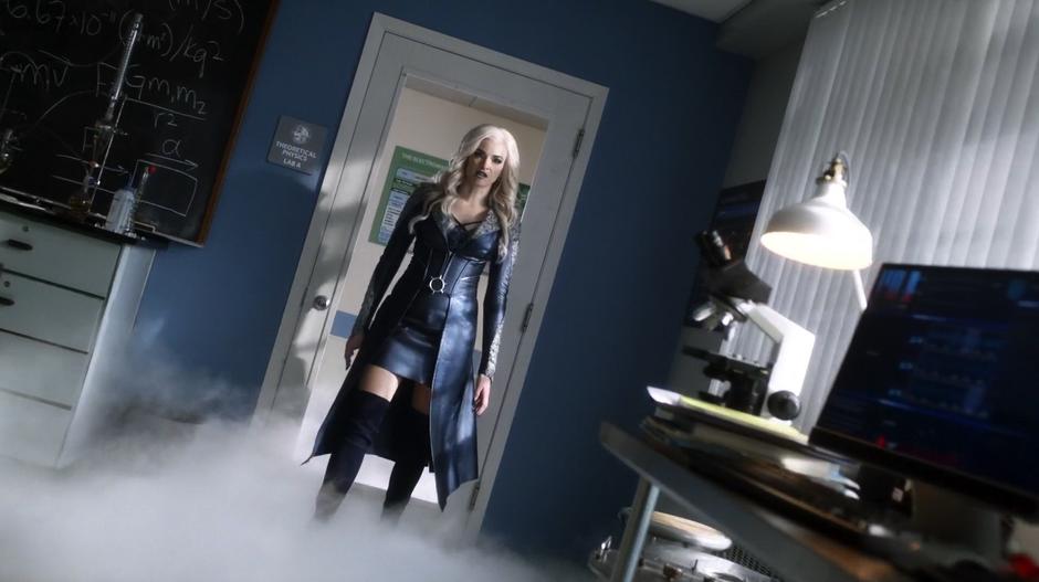 Caitlin in full-on Killer Frost mode steps into the room through the shattered glass door while the ground is covered in fog.