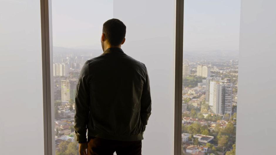 Lito looks through the window out over the city.