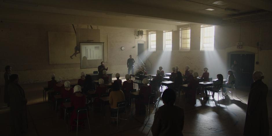 Aunt Lydia teaches the assembled handmaids-in-training about the decline in births.