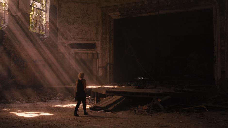 Riley walks towards the stage in the basement of the church.