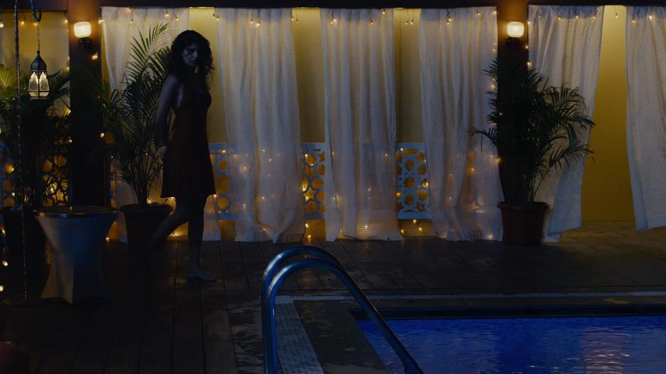 Kala walks up to the edge of her rooftop pool at night.