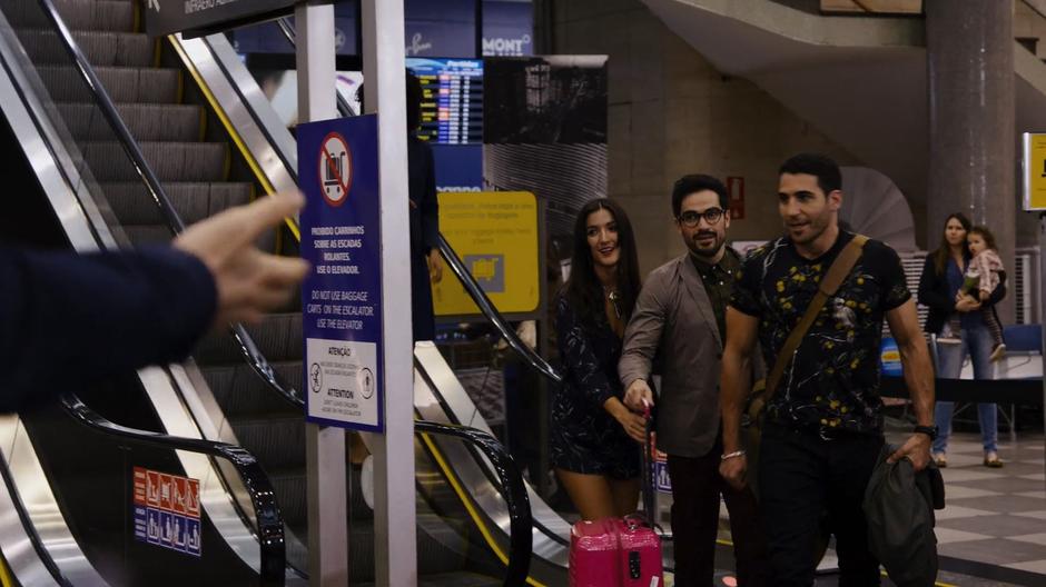 Lito, Hernando, and Dani step off the escalator and approach the waiting fans.