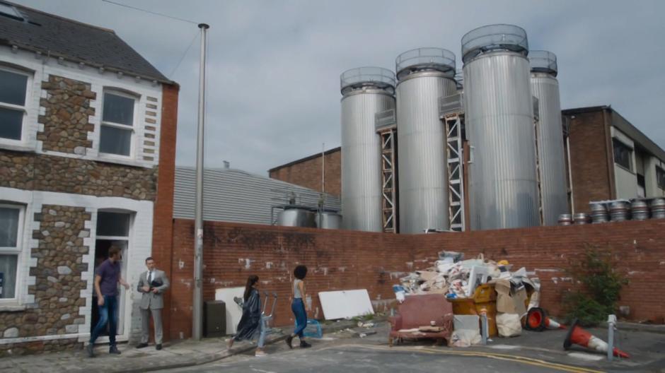 Bill and Shireen walk over to look at the factory after hearing the loud siren and Paul pokes his head out the door where the estate agent is standing.