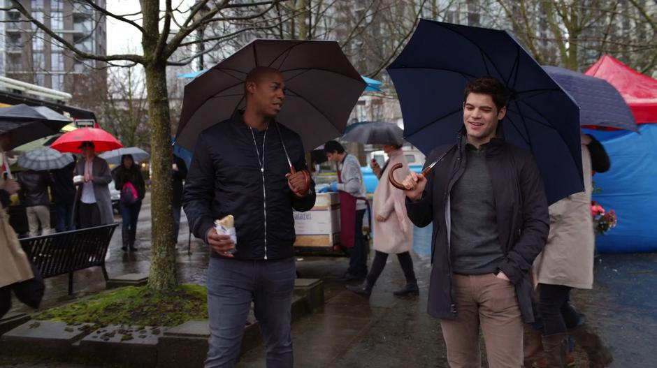 James and Winn walk through the market with their umbrellas talking about the takedown the night before.