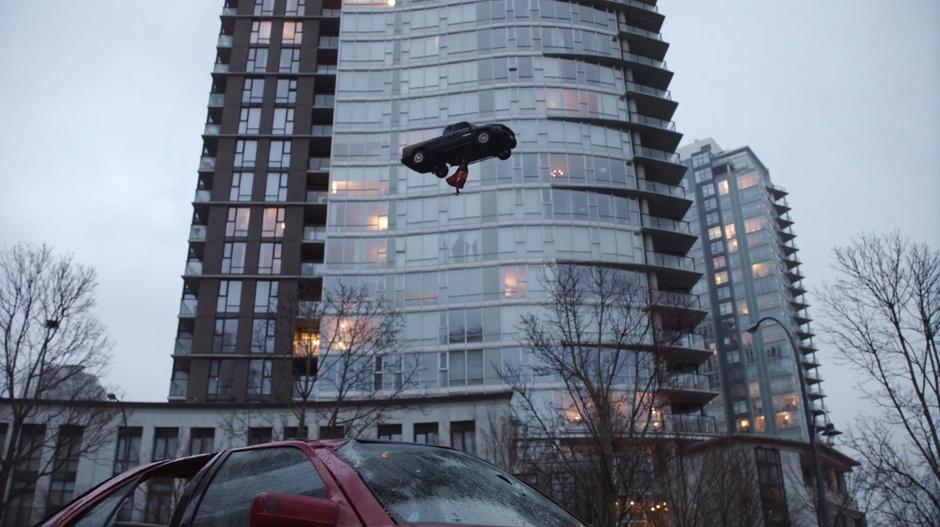 Kara catches a car thrown into the air before it hits a building.