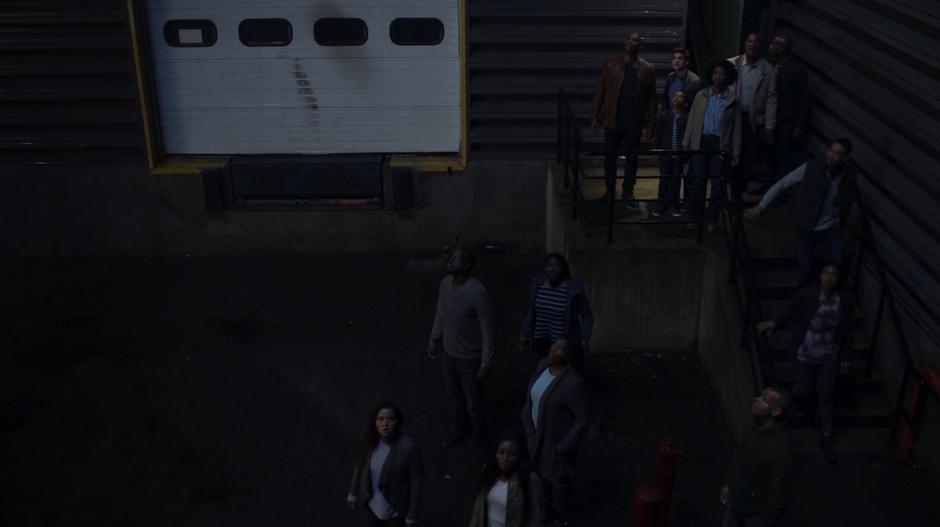 James, Winn, Marcus, Erika, and the other aliens look up into the sky outside the warehouse.