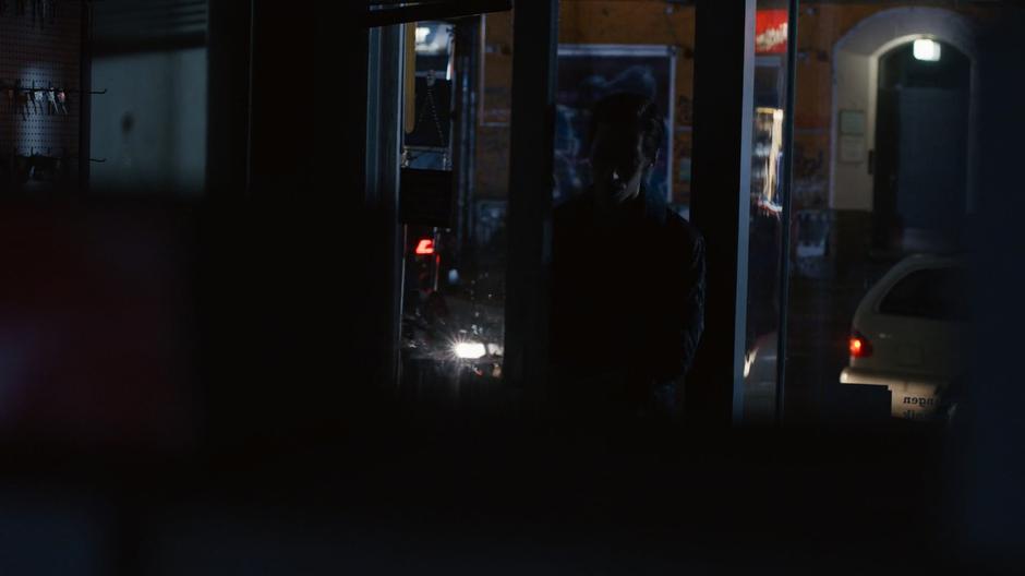 Felix enters the front door of the darkened shop.