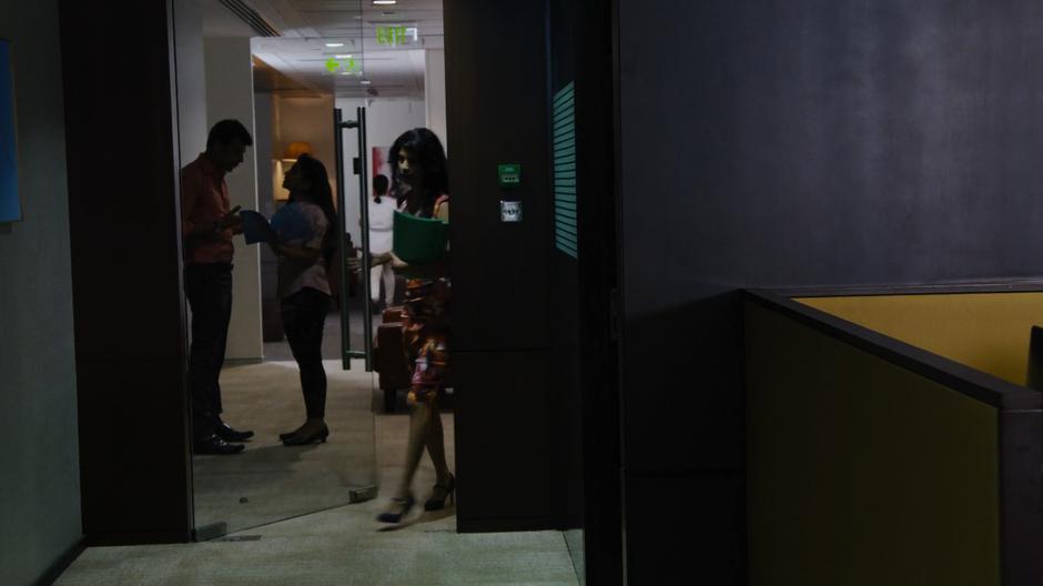 Kala walks into the lobby outside Rajan's office with several folders in her arm.