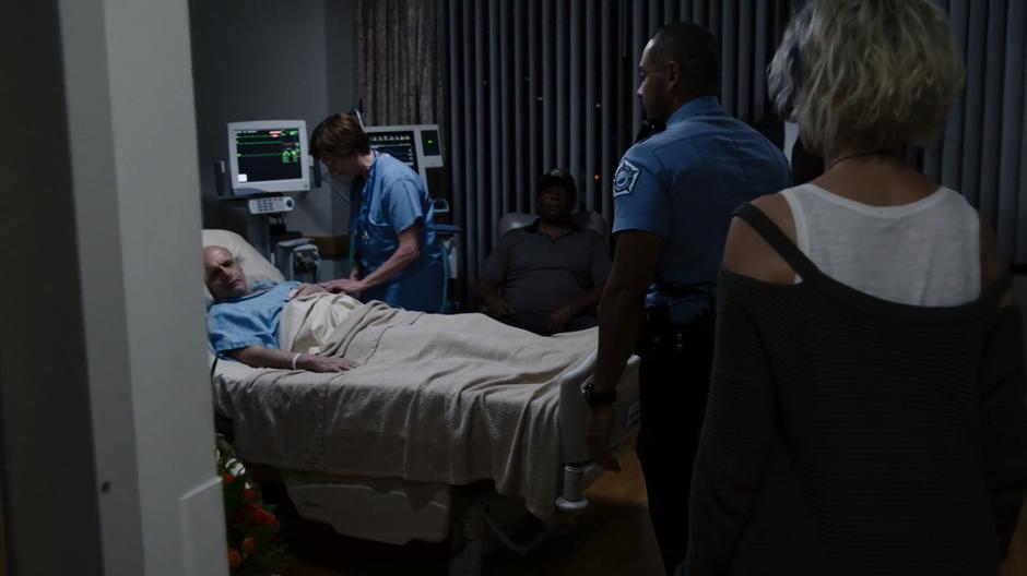 Diego and Riley enter the hospital room where Michael is lying on the bed being attended to by a nurse.