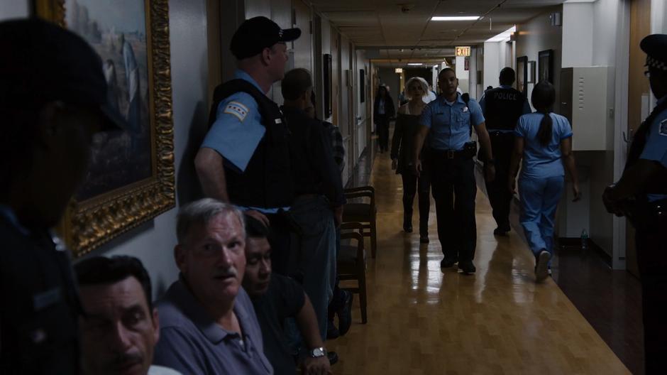 Riley follows Diego down the hospital hallway filled with cops.