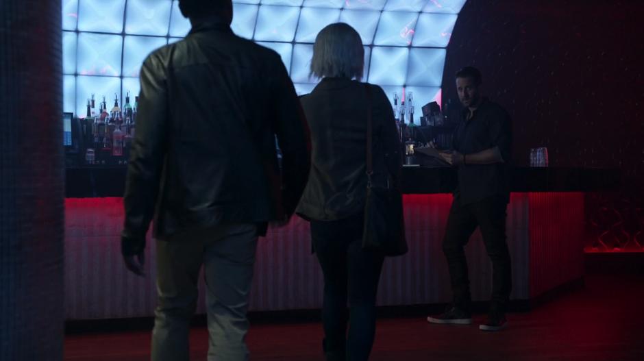 Clive and Liv approach the nightclub owner she is going over paperwork at the bar.