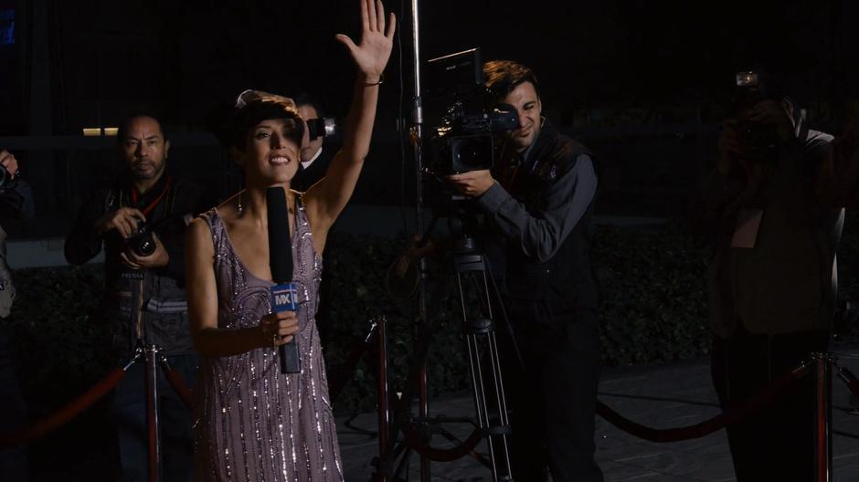 The reporter attempts to get Lito's attention while her camera operator films him.