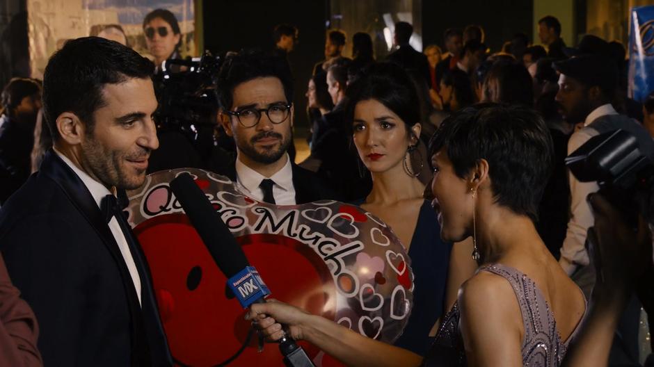 Lito answers the reporter's question while Hernando and Dani watch with concerned looks.