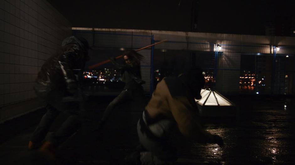 Dinah takes down two of the goons with a staff.